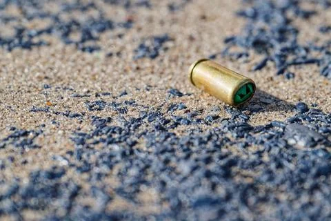 Bullet casing on sand with small dark pebbles scattered Foto stock