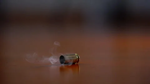 Bullet shell casing falling to wooden surface in slow motion. Fired brass casing Stock Footage 334021410