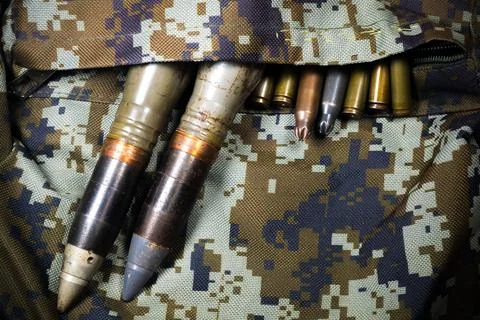 Bullets, shells, cartridges and projectiles on khaki camouflage backpack. L.. Stock Photos