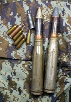 Bullets, shells, cartridges and projectiles on khaki camouflage backpack. L.. Stock Photos
