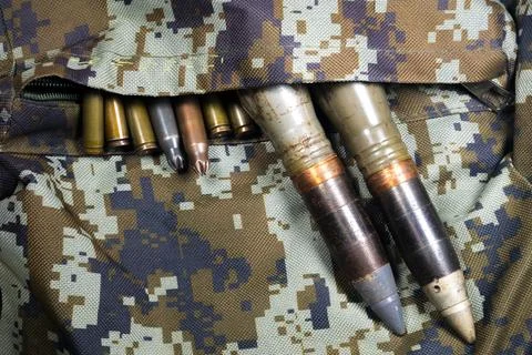Bullets, shells, cartridges and projectiles on khaki camouflage backpack. L.. 스톡 사진