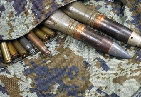 Bullets, shells, cartridges and projectiles on khaki camouflage backpack. L.. Stock Photos