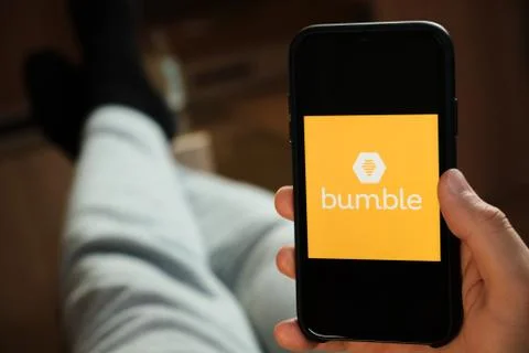 Bumble application on the smartphone in mans hand. Man laying and using Stock Photos