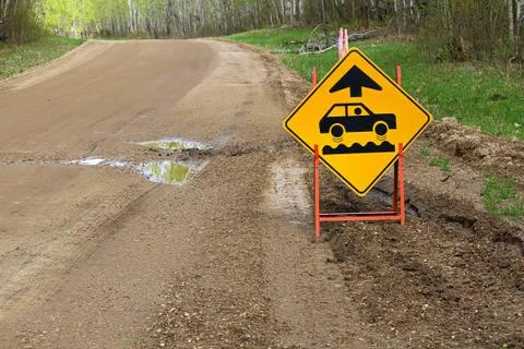 A bumpy road ahead sign with a large pothole Stock Photos