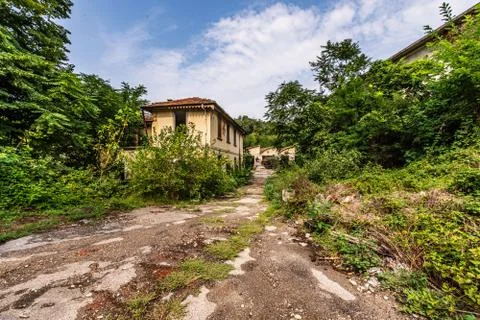 Bumpy road that leads to a large abandoned industrial complex Stock Photos