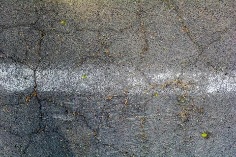 Bumpy road painted white line marking of gray cracked asphalt. Travel concept Stock Photos