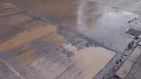 Bumpy road with water risks, Closeup of dangerous road surface with standing Stock Footage 319199692