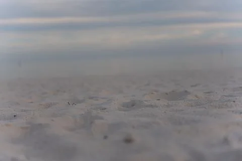 Bumpy sand in a selective focus with sea and sky blurred in the background Stock Photos