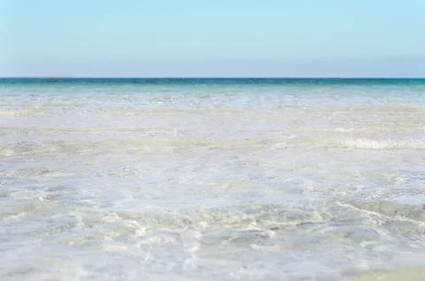 Bumpy tropical sandy beach with blurry transparent ocean and blue sky Stock Photos