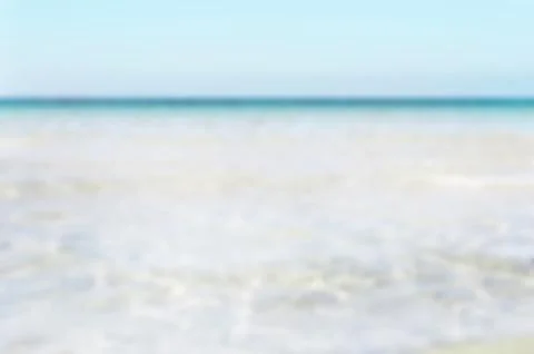 Bumpy tropical sandy beach with blurry transparent ocean and blue sky Stock Photos