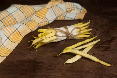 Bunch and several pods of flat runner bean pods heap with yellow kitchen to.. Stock Photos