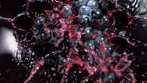 Bunch of black grapes falling into red wine and flying splashes Stock Footage 268743966