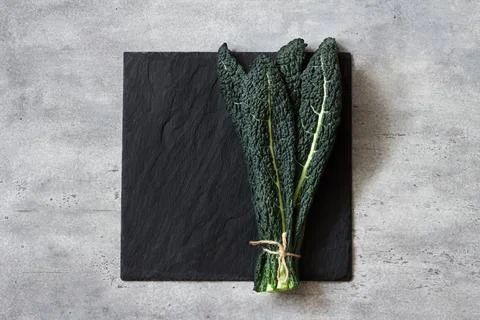 Bunch of black tuscan kale, cavolo nero or lachinato kale on a black slate board Stock Photos