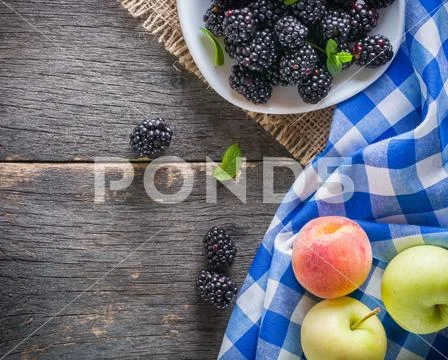 A bunch of blackberries on a white saucer. Gray wooden background. Stock Photos