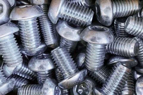 A bunch of bolts threaded round head lie in a chaotic manner. Stock Photos
