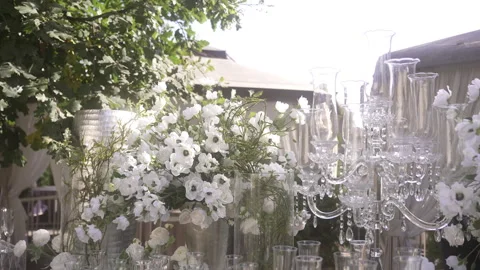 A bunch of candles are sitting on a table next to a bunch of white flowers Vidéo 265572555