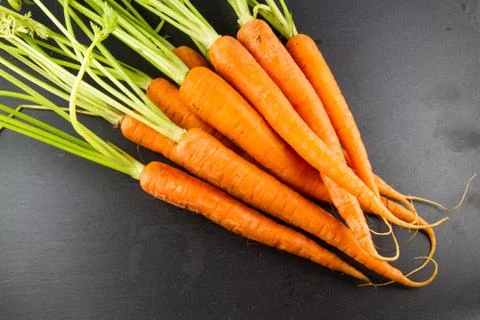 Bunch of carrots on dark slate background. Stock Photos