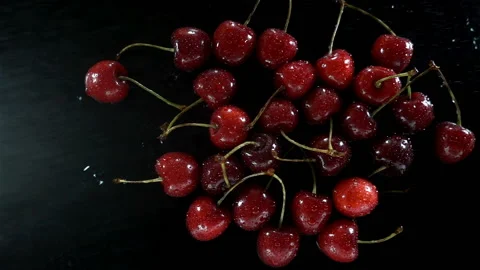 A bunch of cherry berries in slow motion on a wet black Stock Footage 134243373