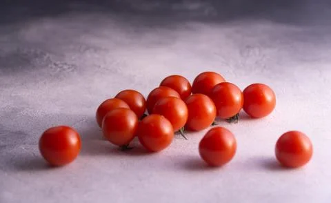 Bunch of cherry tomatoes on white stone concrete table, side view with copy Stock Photos
