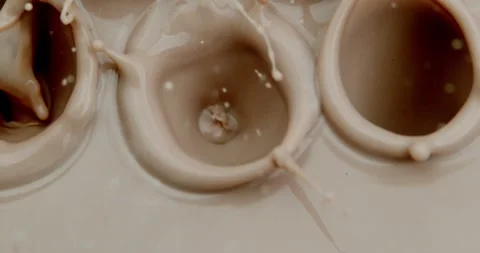 A bunch of chocolate chips fall in slow motion into chocolate milk Video stock 259995280