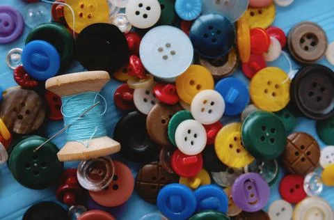 A bunch of colored buttons and a spool of thread and a needle Stock Photos