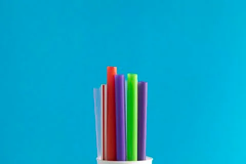 Bunch of colored plastic straws isolated on blue background close up. Ban sin Stock Photos