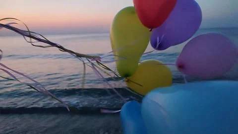 Bunch of colorful inflatable balloons on background of sea at dawn and sunset Stock Footage 306768017