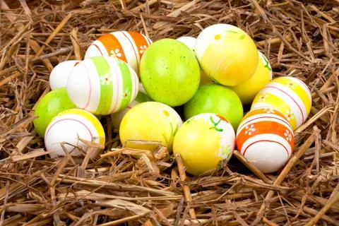 Bunch of colorful painted easter eggs hidden in a nest of straw Stock Photos