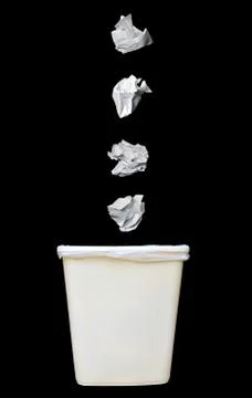 Bunch of crumbled paper being throwing into a trash bin or waste bin isolated Fotos Stock