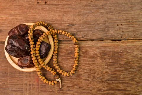 Bunch of dates and Islamic prayer beads on wooden board with copy space. Rama 写真素材