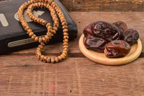 Bunch of dates, islamic prayer beads and holy quran on wooden board with copy 写真素材