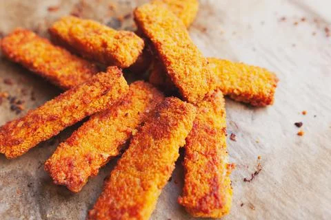Bunch of deep fried, crispy fish fingers on greasy parchment paper Foto stock