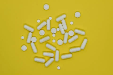 Bunch of different forms white medication pills on yellow background surface Stock Photos