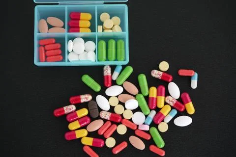Bunch of different medications, tablets, pills and capsules on a black matte Stock Photos