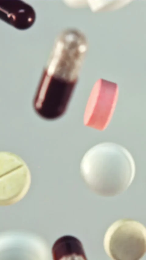 A bunch of different pills fly up and rotate in flight. Filmed is slow motion Stock Footage 335293043