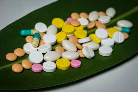 A bunch of different pills on a green leaf Stock Photos