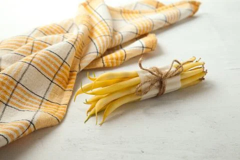 Bunch of flat runner bean pods heap and yellow kitchen towel on wooden whit.. Stock Photos