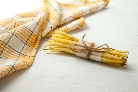 Bunch of flat runner bean pods heap and yellow kitchen towel on wooden whit.. Stock Photos