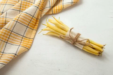 Bunch of flat runner bean pods heap and yellow kitchen towel on wooden whit.. Stock Photos