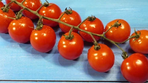 Bunch of fresh cherry tomatoes on a blue wooden Stock Footage 83334660