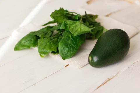 Bunch of fresh spinach and avocado on a white wooden background Stock Photos