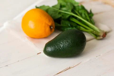 Bunch of fresh spinach, orange and avocado on white wooden background Stock Photos