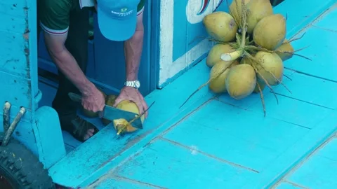 A bunch of fresh tender green coconuts and a man cutting their 库存影片 333350080