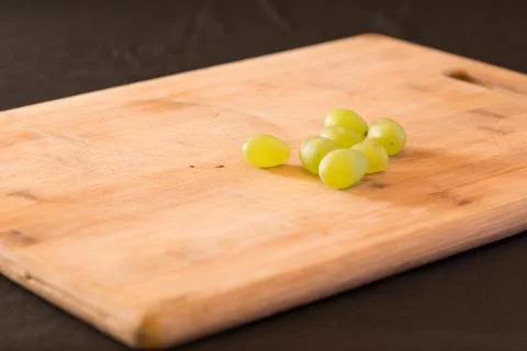 A bunch of grapes of a wooden chopping board.NEF Stock Photos