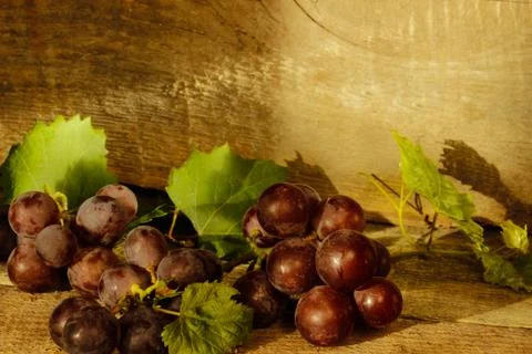 A bunch of grapes on a wooden surface Stock Photos