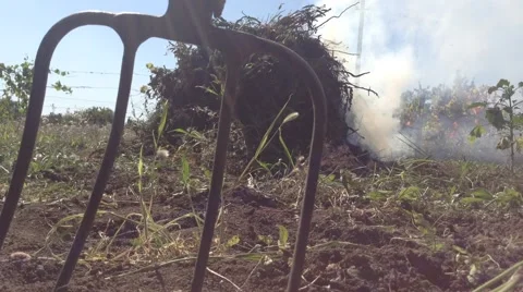 A bunch of grass is burning and smoking in the village And pitchfork Stock Footage 58300224