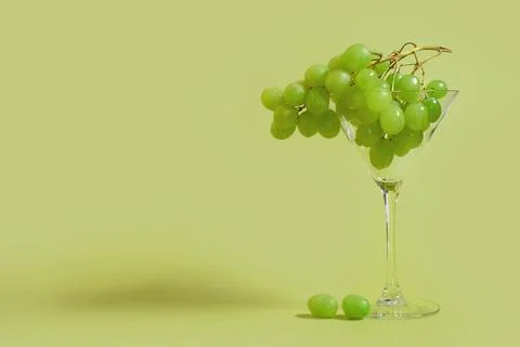 A bunch of green grapes in a martini glass on a colored background Stock Photos