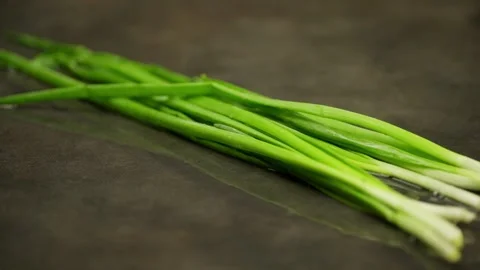 A bunch of green onions falls on the table, forming splashes of water. Stock Footage 270156937