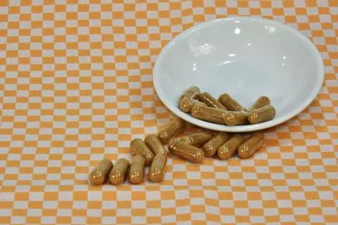 A bunch of green tea, on leaf capsules or pills on dishes. Stock Photos