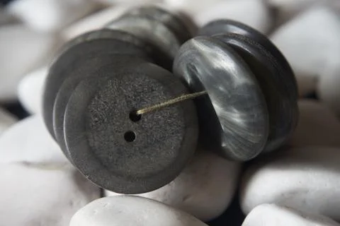 Bunch of grey buttons tied up with thread on white stones backgr Stock Photos